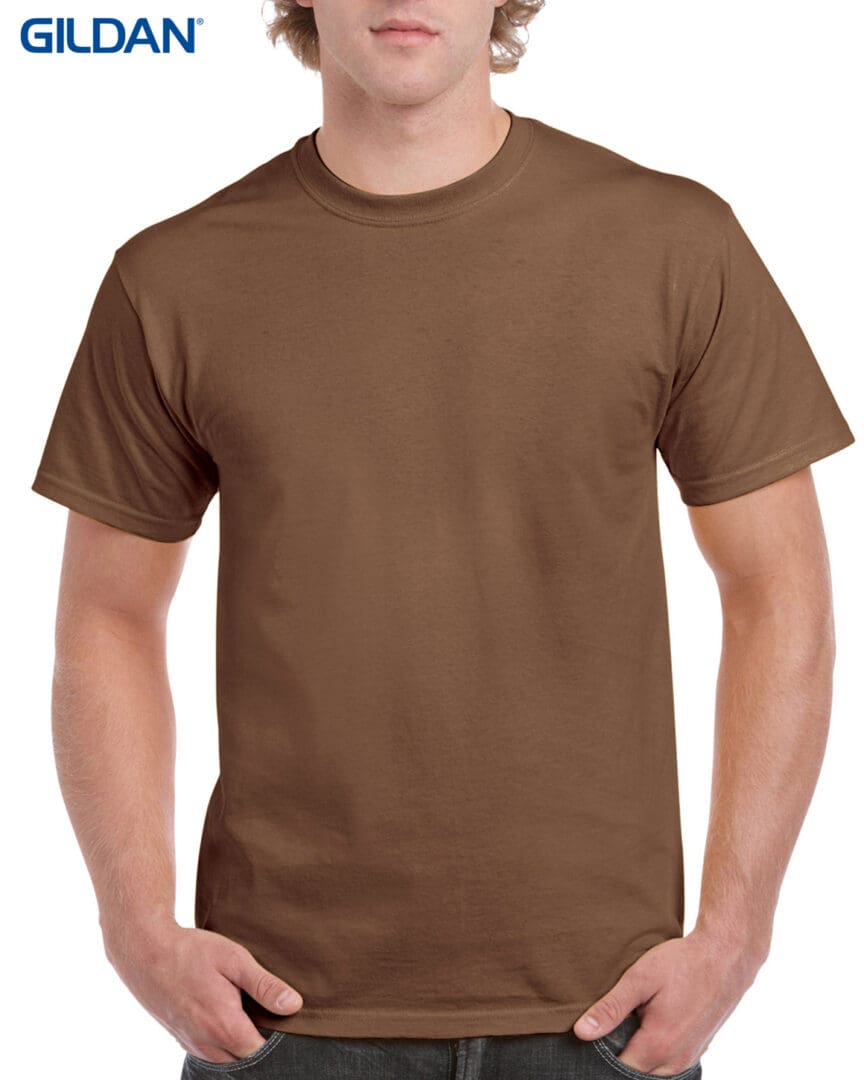 A man wearing brown t-shirt with hands in his pockets.