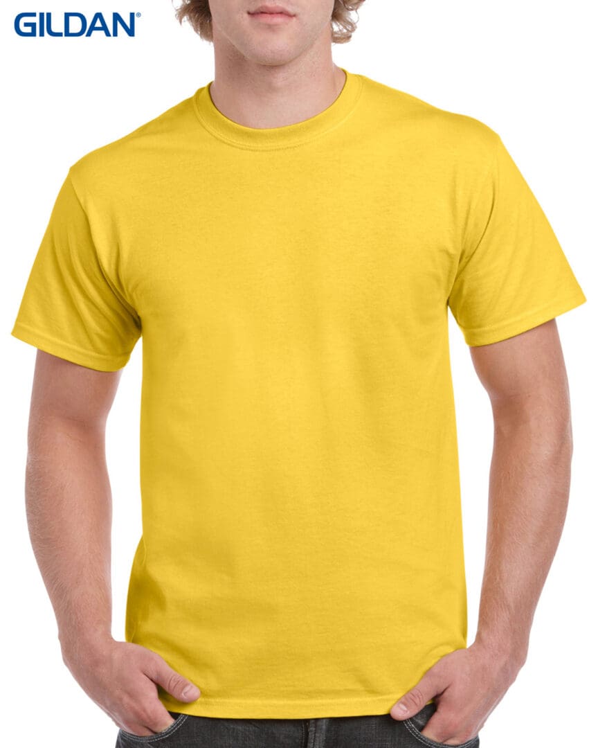 A man wearing a yellow shirt with his hands in his pockets.